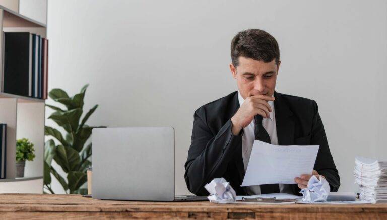 Perplexed, Puzzled Handsome Businessman Looking At Laptop Screen At Workplace In Office.