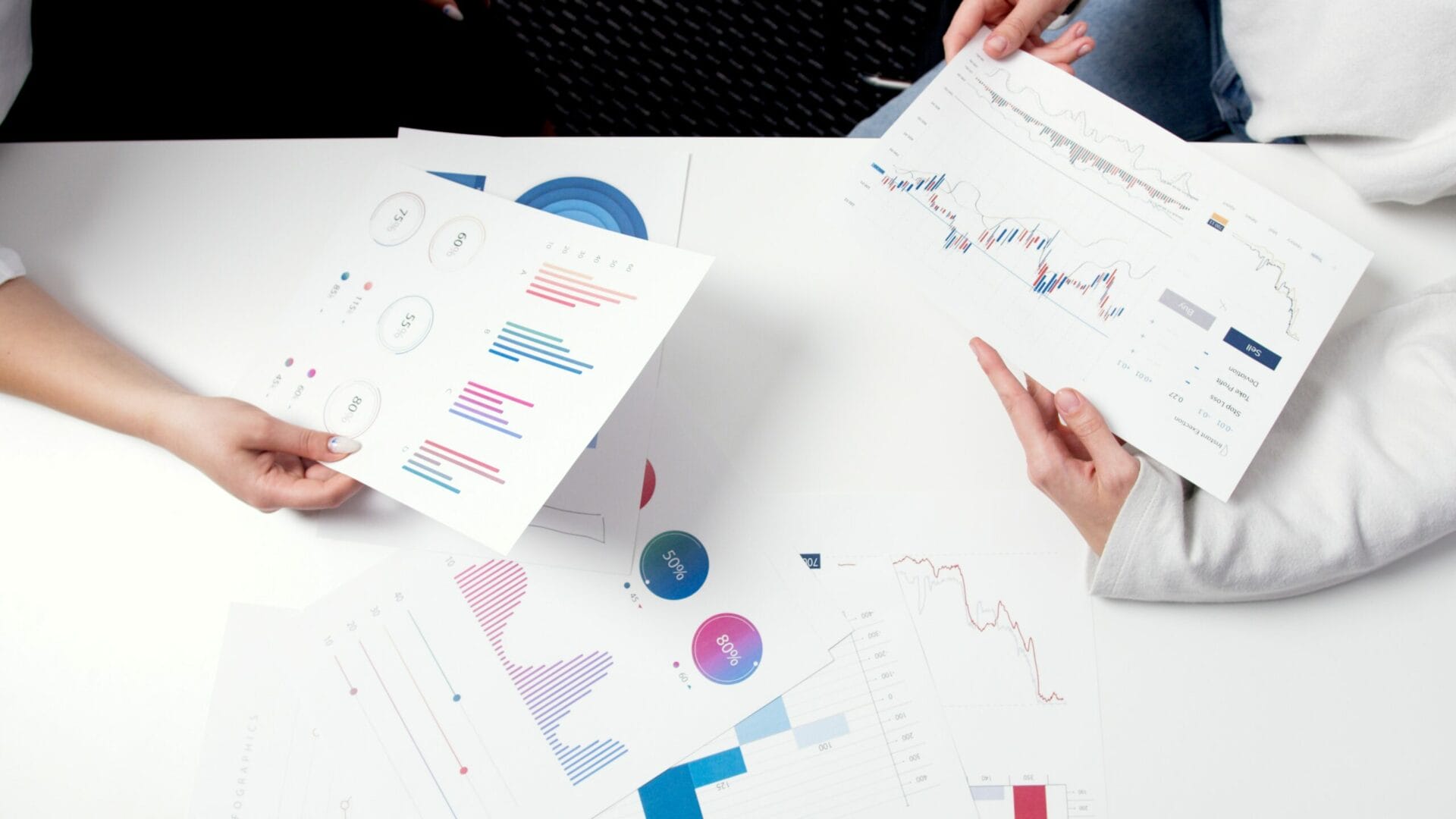 Persons analyzing trends and graphs from their printed copy.