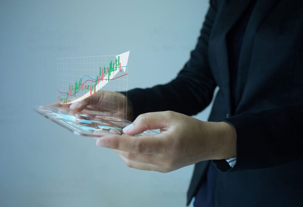 A hand holding a glass tablet showing a 3D graph of inside bar graph.