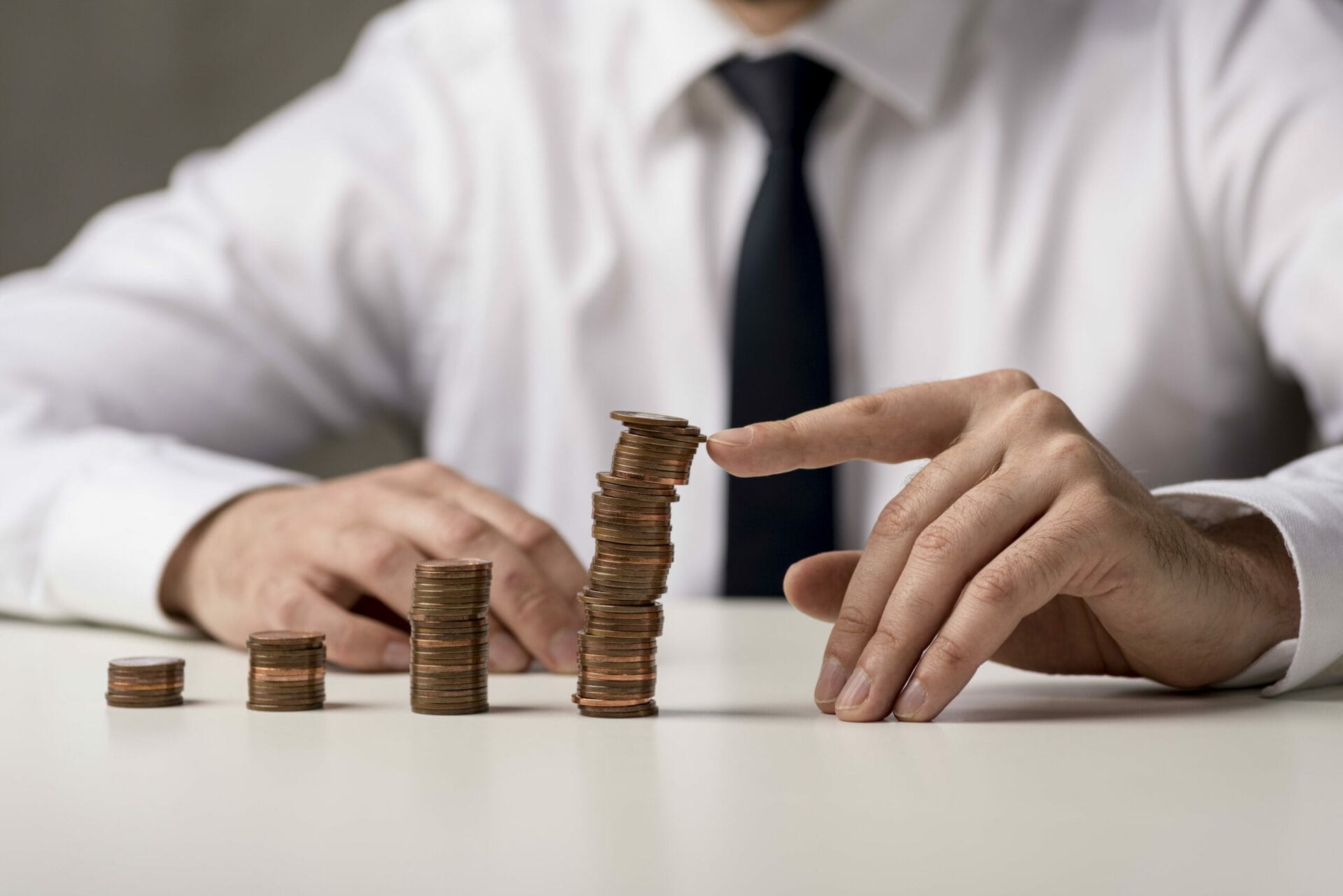 A business man building a stack of dime coins.