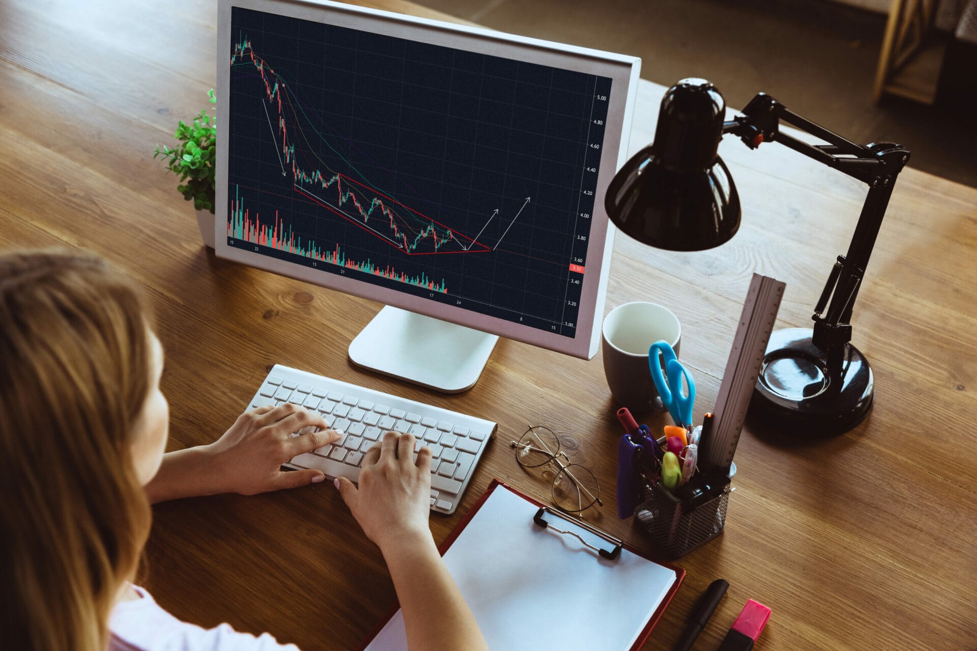 A women in front of her Personal Computer engage in trading as her screen show a trading graph.